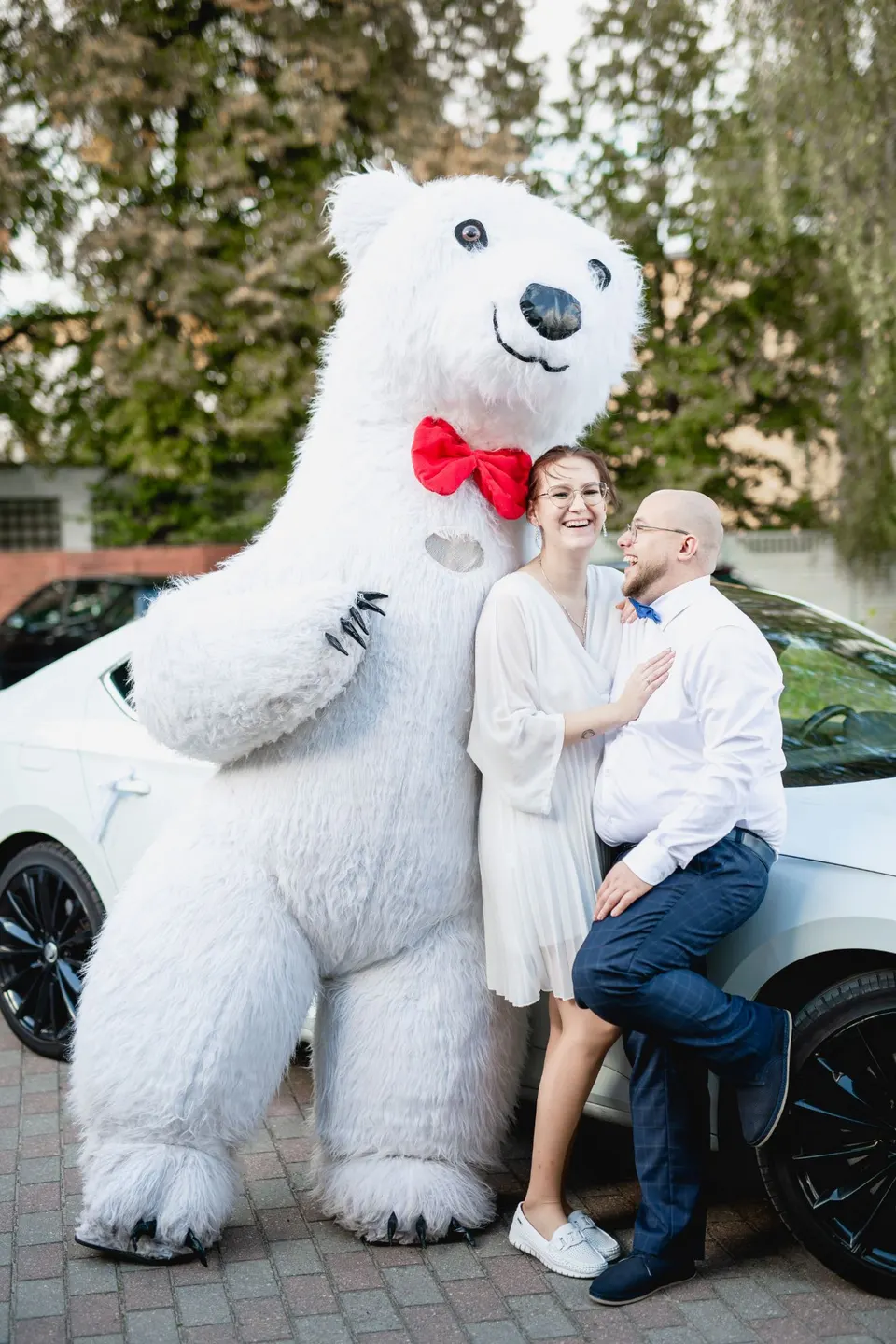 Oliwia i Mikołaj — Czuły Punkt Nowiccy — śmieją się przy białym samochodzie, obok wielki biały miś z czerwoną muszką